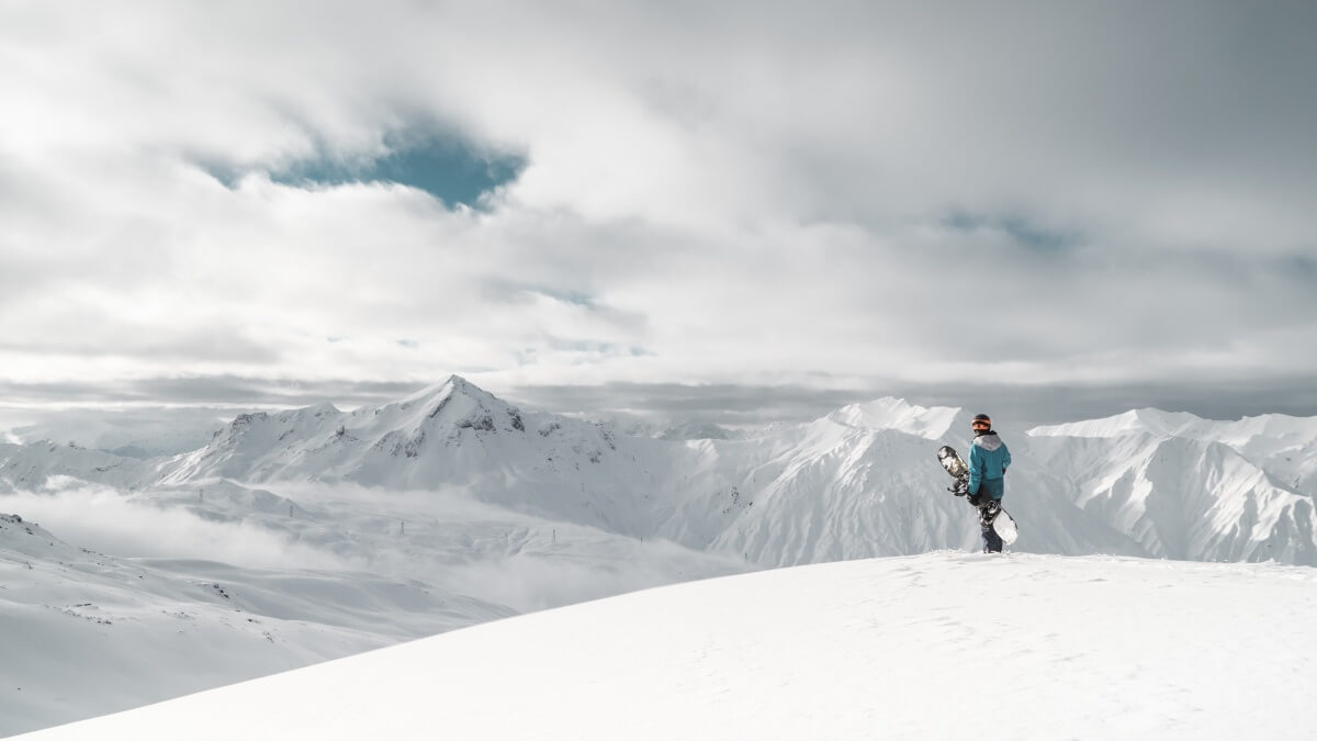 skier standing at the top of a mountain with the alps in the background