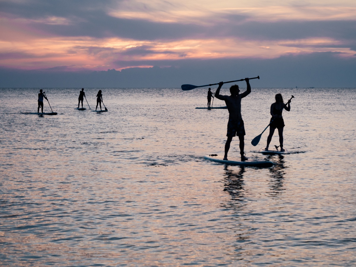 several people on a stand-up paddle board