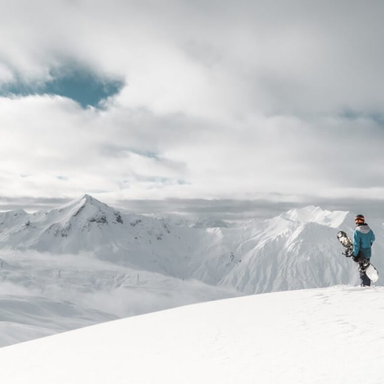 skier standing at the top of a mountain with the alps in the background